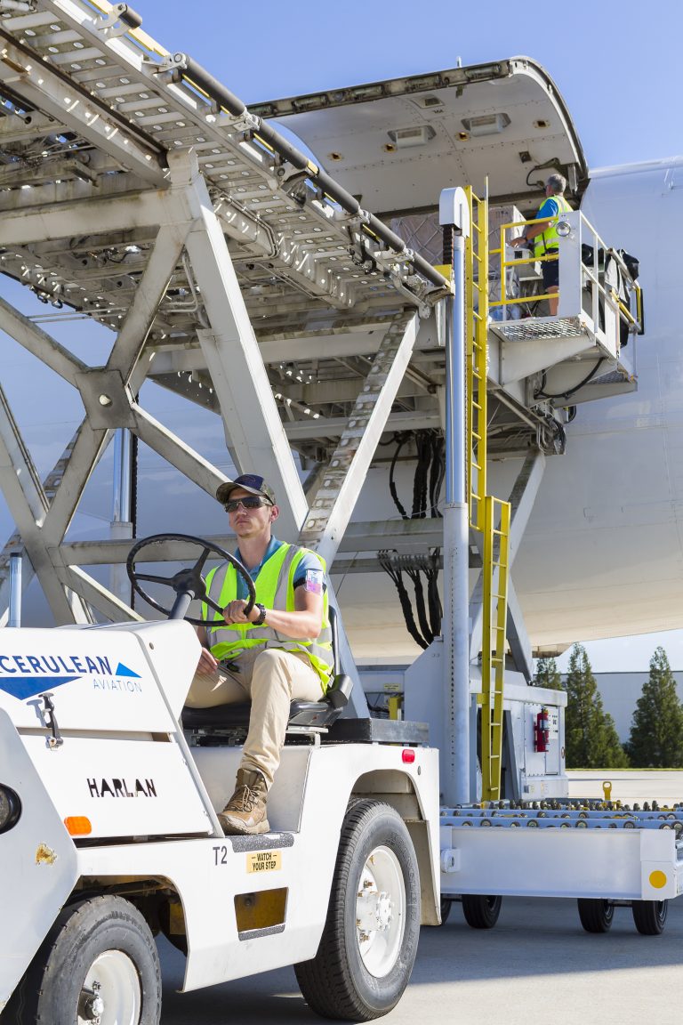 Kloader and man on tug unloading cargo plane